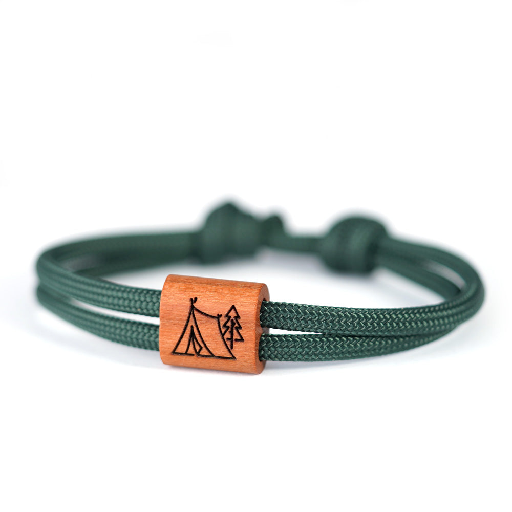 Verstellbares Outdoor-Armband aus dunkelgrünem Segeltau mit Holzschieber und Camping-Gravur (Zelt im Wald).