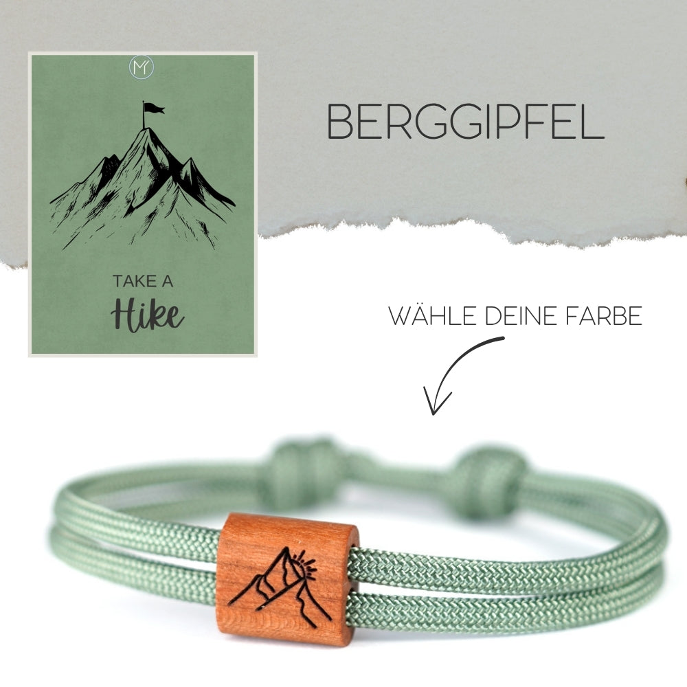 Verstellbares Outdoor-Armband aus grünem Segeltau mit Holzschieber und Berggipfel Motiv Gravur mit Schiebeverpackung.