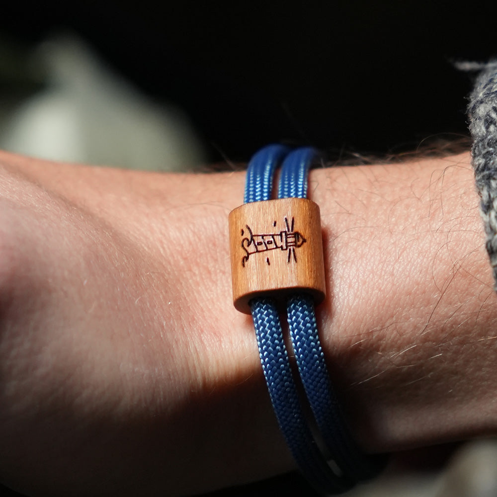 Verstellbares Outdoor-Armband aus dunkelblauem Segeltau mit Holzschieber und Leuchtturm-Gravur.